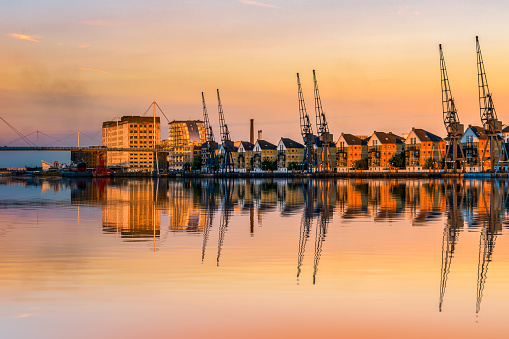 Royal Victoria Dock in London at sunset with dockside cranes and waterfront terraced houses
