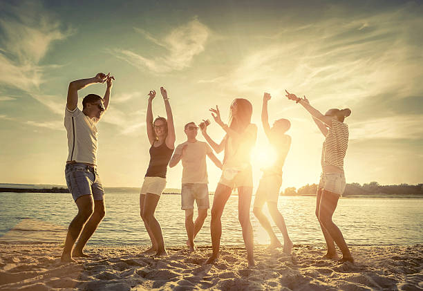 istock Friends funny dance on the beach under sunset sunlight. 604859302