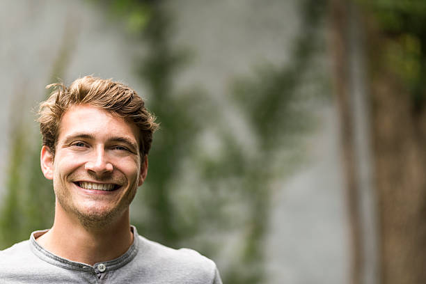 istock Portrait of young man smiling in yard 604861232