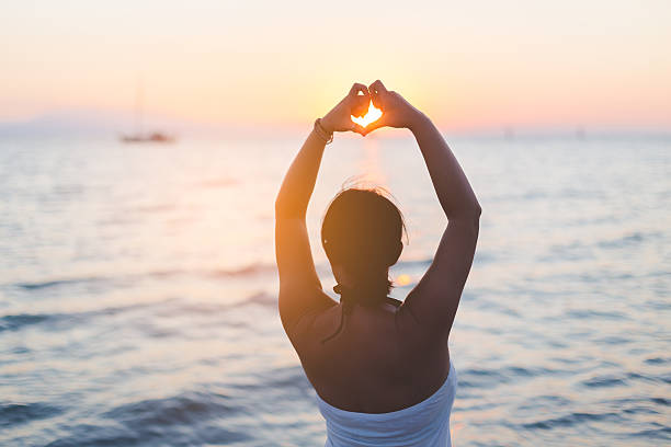 istock Woman making heart shape on the beach 604865046