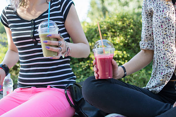 istock Young women talking and having fruit smoothies on sunny day 604866834