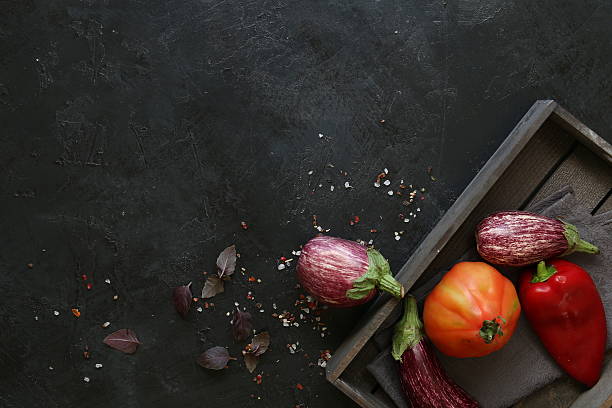 istock Eggplant varieties in black bowl over dark slate background. Overhead 604875034