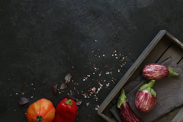 istock Eggplant varieties in black bowl over dark slate background. Overhead 604876612