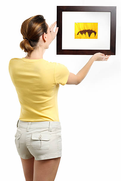 istock Woman hanging picture frame on white 604895082