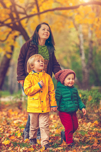 istock Mother with children in autumn park 604903522