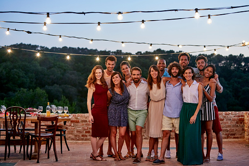 Full length portrait of happy friends standing together at patio during social gathering