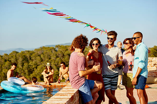 Friends enjoying drinks at poolside Happy multi ethnic friends enjoying drinks at poolside during social gathering beer alcohol stock pictures, royalty-free photos & images