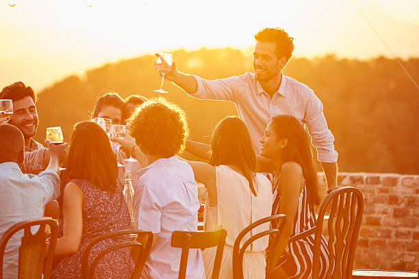 man toasting wineglass with friends at party - drinking wine stockfoto's en -beelden