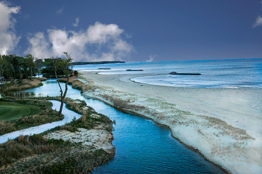 Surreal, twilight view of inland waterway and sand along a cost