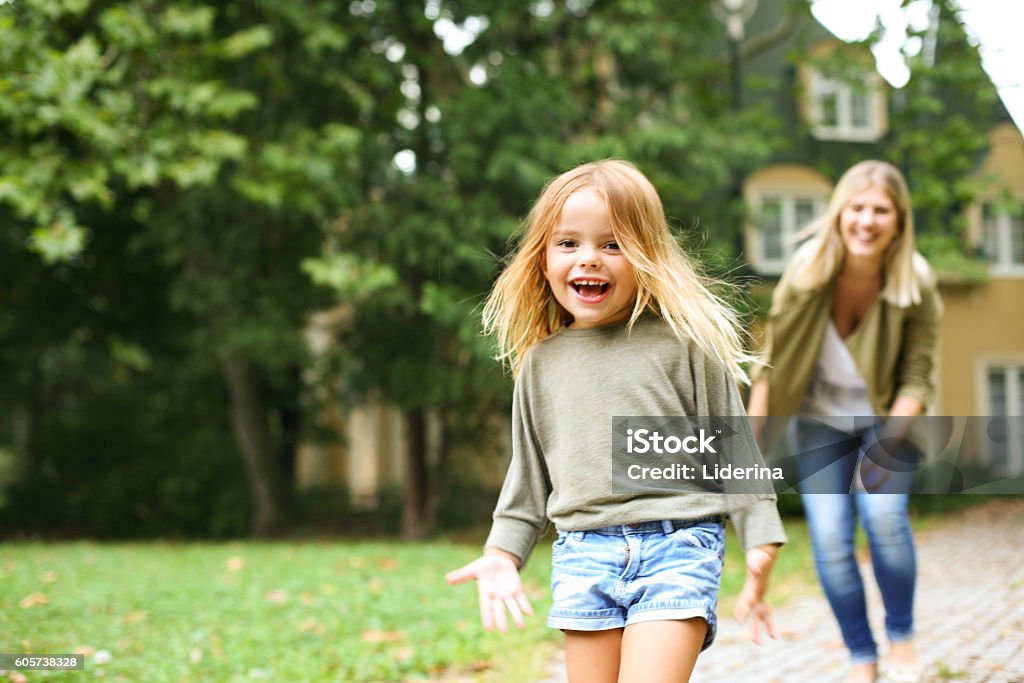 Mother chasing girl outdoor. Mother chasing cheerful girl outdoor. Focus is on girl in the front. Child Stock Photo