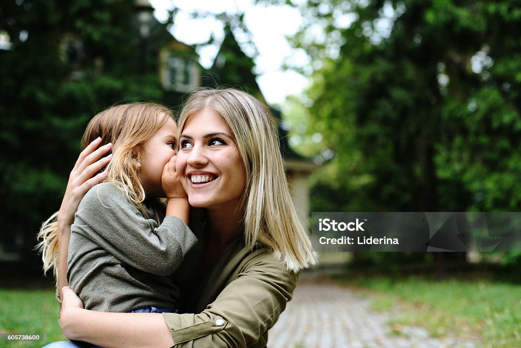 Hija susurrando al oído de las madres. - Foto de stock de Niño libre de derechos