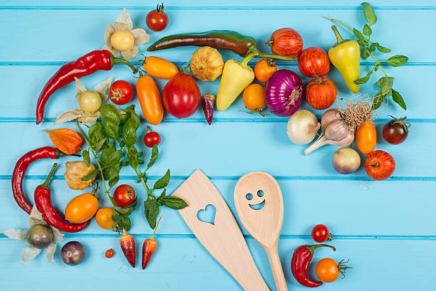 istock Fresh vegetables with wooden spoons and stirrers on blue background. 605738818