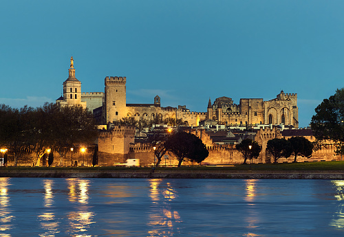Avignon, France - April 8, 2016: Avignon skyline. Riverside night view of The Papal Palace at night, one of the largest and most important medieval Gothic buildings in Europe. Provence-Alpes-Cote d'Azur. France