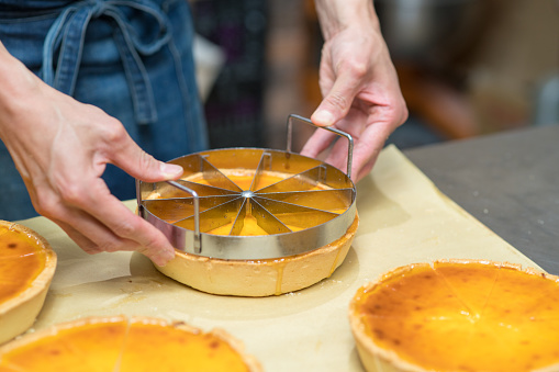 Baker cutting a freshly baked cake ready for sale. Kyoto, Japan. May 2016