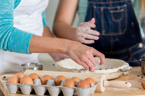 istock Mother and daughter working with dough to bake a pie 605745106