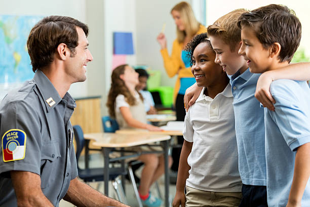 istock Friendly police officer talks with school friends 605745362