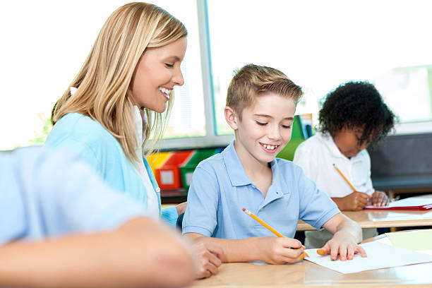 istock Pretty teacher assists cute young boy with his schoolwork 605745390
