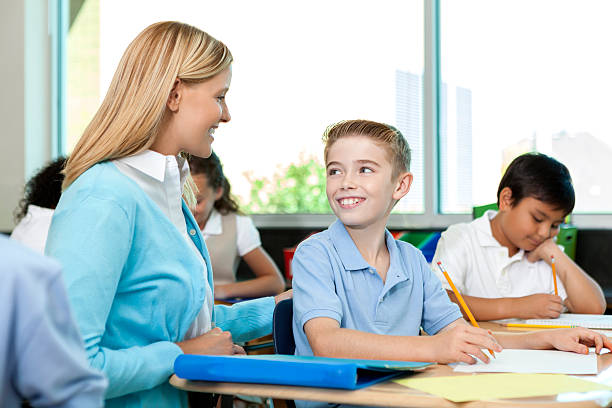istock Pretty teacher helps cute young boy with his schoolwork 605745398
