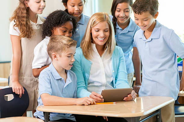 istock Students and teacher look at homework on a digital tablet 605745404