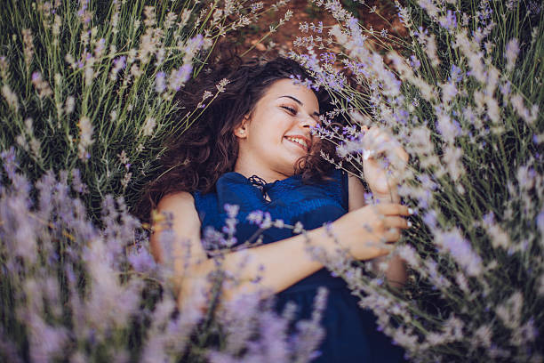 Beautiful young woman sitting in lavender field