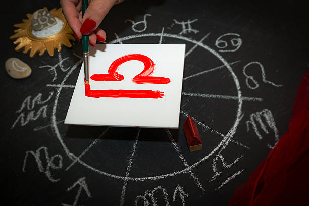 Female astrologer draws libra zodiac sign on white tile
