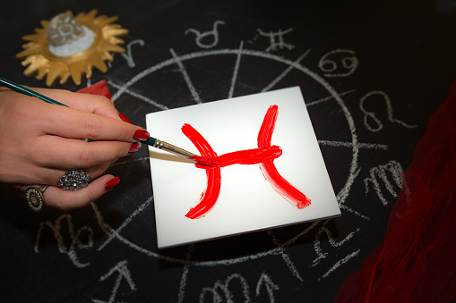 La astróloga femenina dibuja el signo del zodiaco de Piscis en baldosas blancas photo