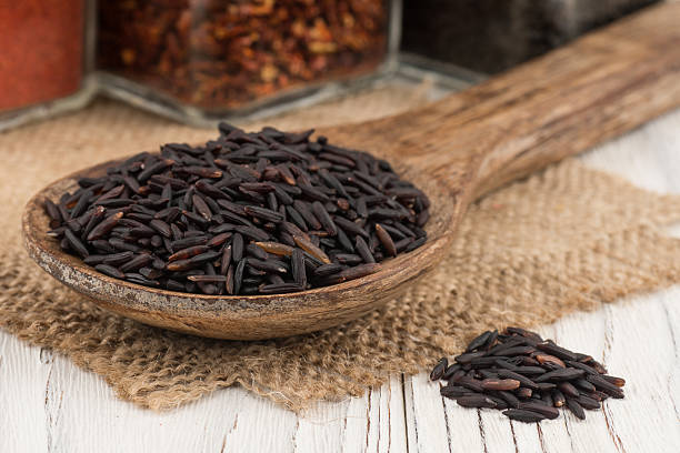 istock Black rice in a wooden spoon on old wooden table. 605752946