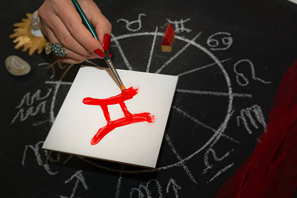 istock Female astrologer draws gemini zodiac sign on white tile 605753024