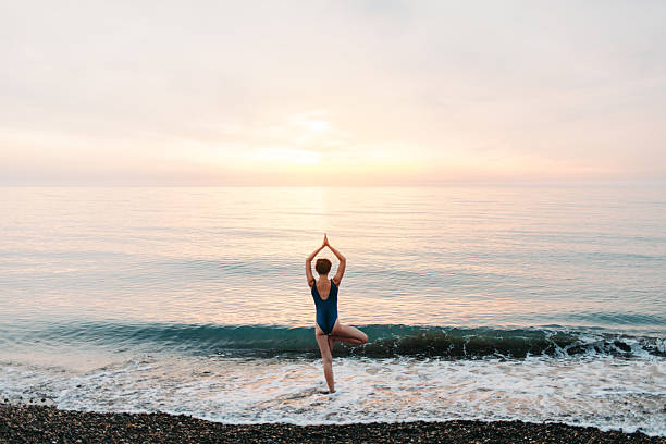 istock Girl doing yoga on beach 605755424