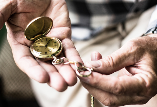 Old hands hold an antique pocket watch