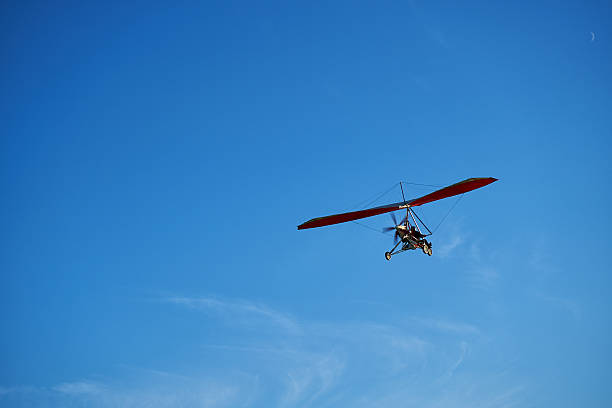 istock Red motor hang glider flying in the blue sky. 605756656