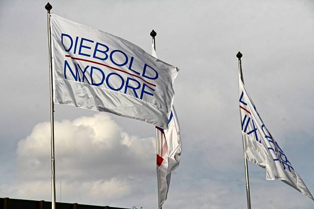 flags and banners of Wincor Diebold company, Paderborn, Germany Paderborn, Germany - September 16, 2016: Acquisition of Wincor Nixdorf AG, Paderborn by the US company Diebold. This measure leads to a common working global corporation Diebold Nixdorf. Diebold Nixdorf is represented by 25,000 employees in more than 130 countries. The turnover is about 4.7 billion euros. Almost all of the 100 largest banks and 25 of the largest trading companies are among the customers. Nixdorf and Diebold were previously separated in the software and hardware business operates mainly in the production and support of ATMs in banking and POS systems in retail. paderborn photos stock pictures, royalty-free photos & images