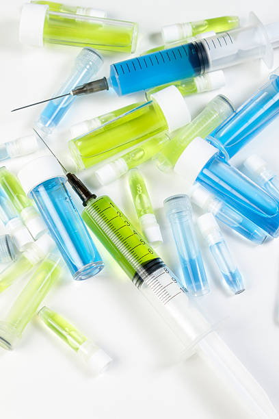 istock Loaded syringe's and vials containing blue and green fluids 605758986