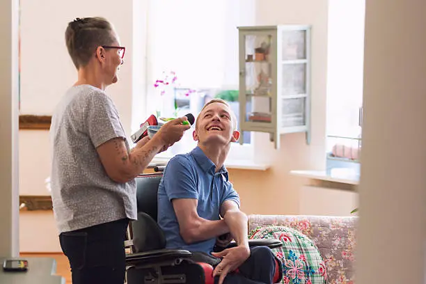 Color image of a real life young physically impaired Cerebral Palsy patient being fed by his mother.