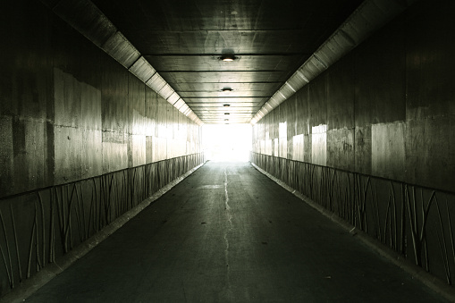  Light illuminates the end of an urban concrete tunnel. In panoramic orientation with copy space.