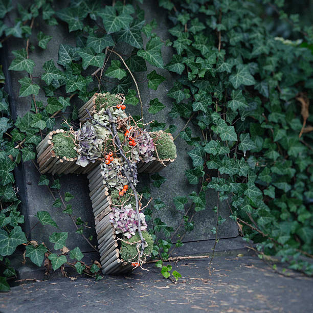 Cross made with moss and dried flowers decorating an old gravestone before All Saints day in Lodz, Poland. Tilt-shift and toning applied for more dramatic look.