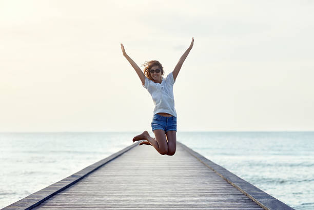 istock Happy jumping girl on the pier 605763322