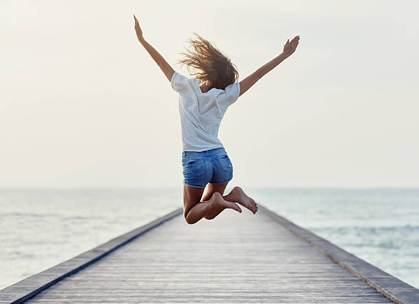 Back view of jumping girl on the pier Back view of jumping girl on the pier. Freedom concept skinny stock pictures, royalty-free photos & images