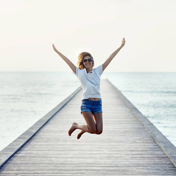 istock Happy jumping girl on the pier 605763432