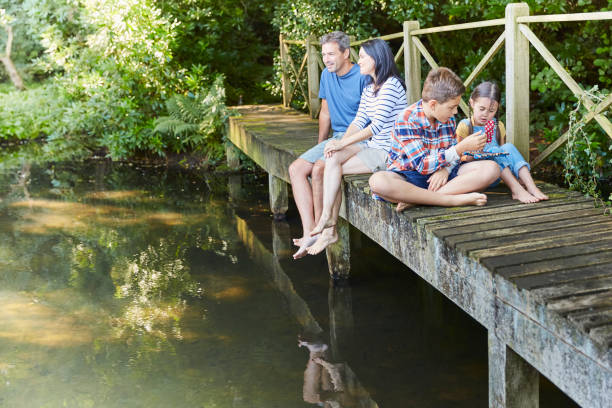 istock Family relaxing on footbridge over pond 605764089