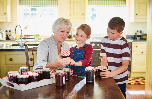 großmutter konserviert marmelade mit enkelkindern in der küche - jar canning food preserves stock-fotos und bilder