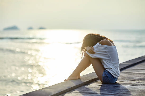 istock Sad lonely beautiful woman sitting on the pier 605766122