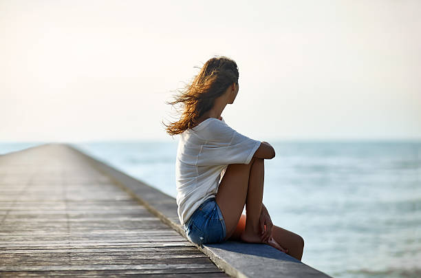 istock Young beautiful woman sitting on the pier 605766616