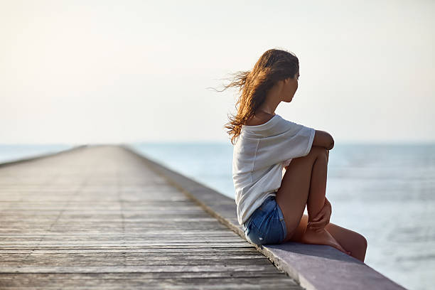 istock Young beautiful woman sitting on the pier 605766642