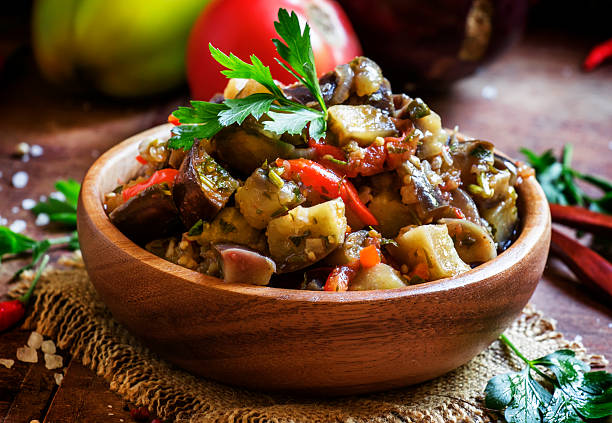 Traditional Caucasian saute from stewed eggplants Traditional Caucasian saute from stewed eggplants, fresh vegetables and herbs on the old wooden background in rustic style, selective focus aubergine stock pictures, royalty-free photos & images