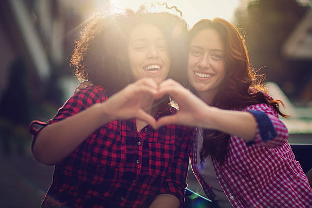 istock Two girlfriends making heart with their hands 605766798