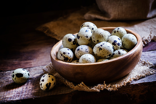 Quail eggs in a bowl, vintage wooden background, rustic style. Low key, selective focus