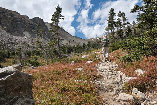 Hiking up a steep trail, a man with a backpack hikes towards the 11,837 foot high Buchanan Pass and the Rocky Mountain Continental Divide in the Indian Peaks Wilderness, Colorado.