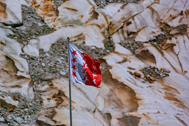 istock Flag Waving Against Rocky Mountain At Alps 605780795