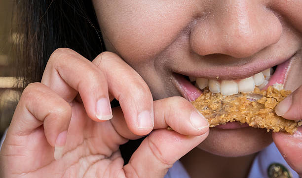 istock close up woman mouth with fried chicken 605780960
